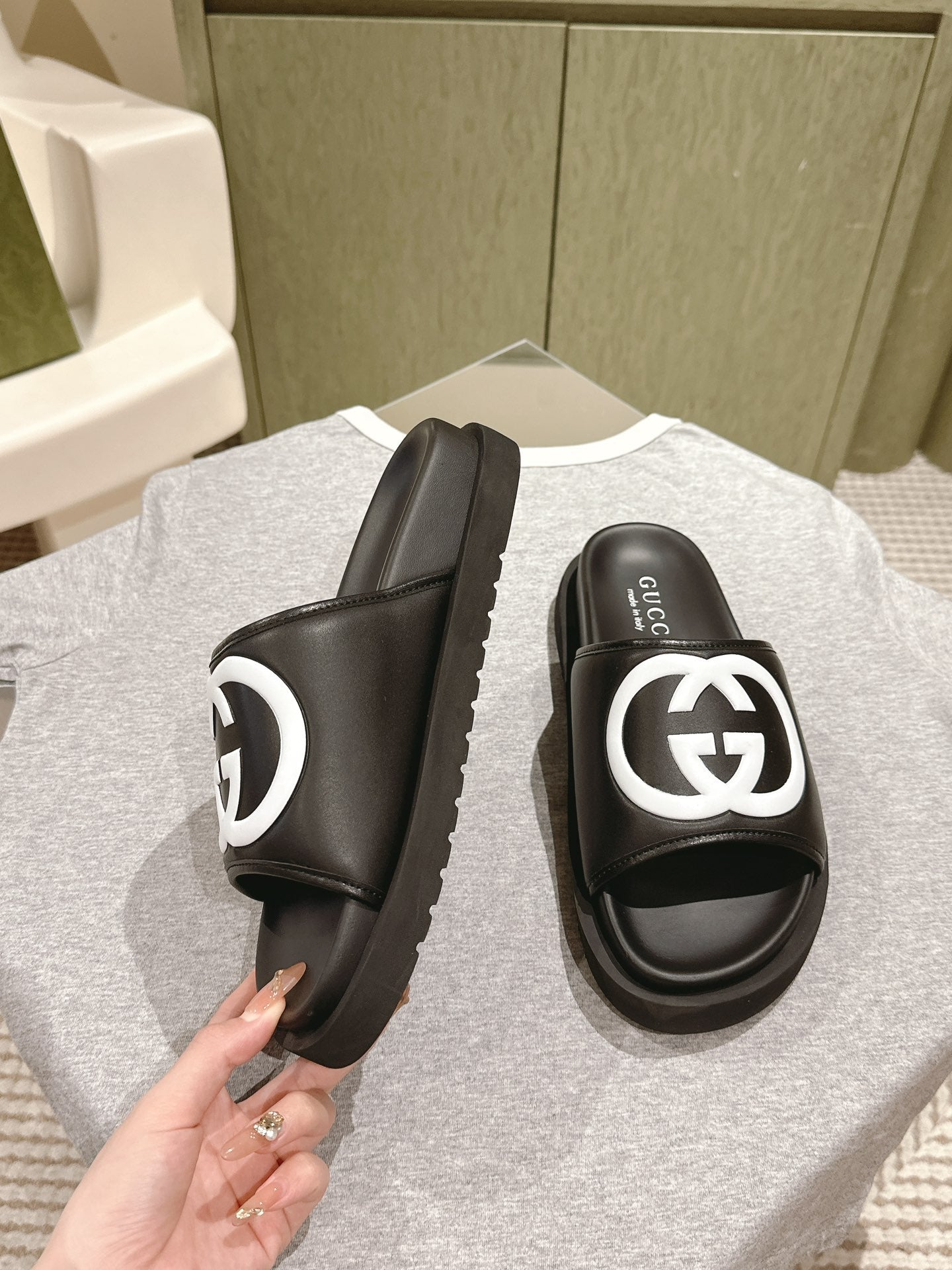 Black slide sandals with white GG logo on wide strap, side and front view