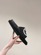Black slide sandal with white GG logo on strap, lifted side view of one shoe