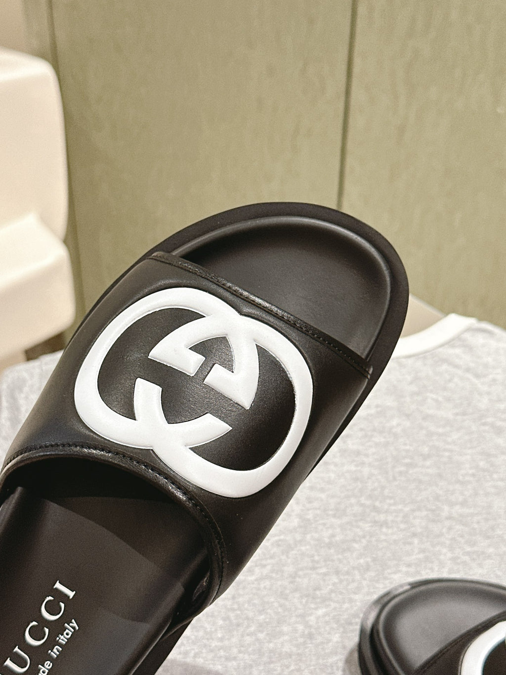 Black slide sandal close-up: white GG logo on the strap over a black sole