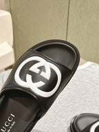 Black slide sandal close-up: white GG logo on the strap over a black sole