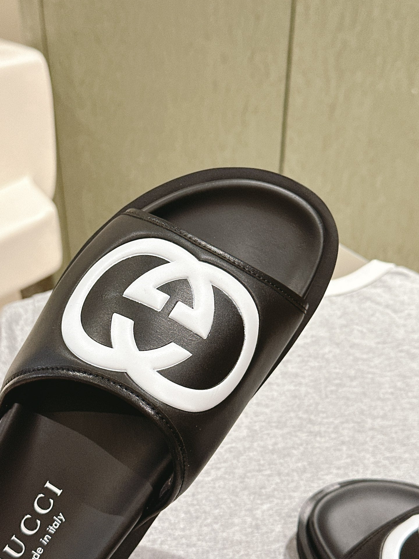 Black slide sandal close-up: white GG logo on the strap over a black sole