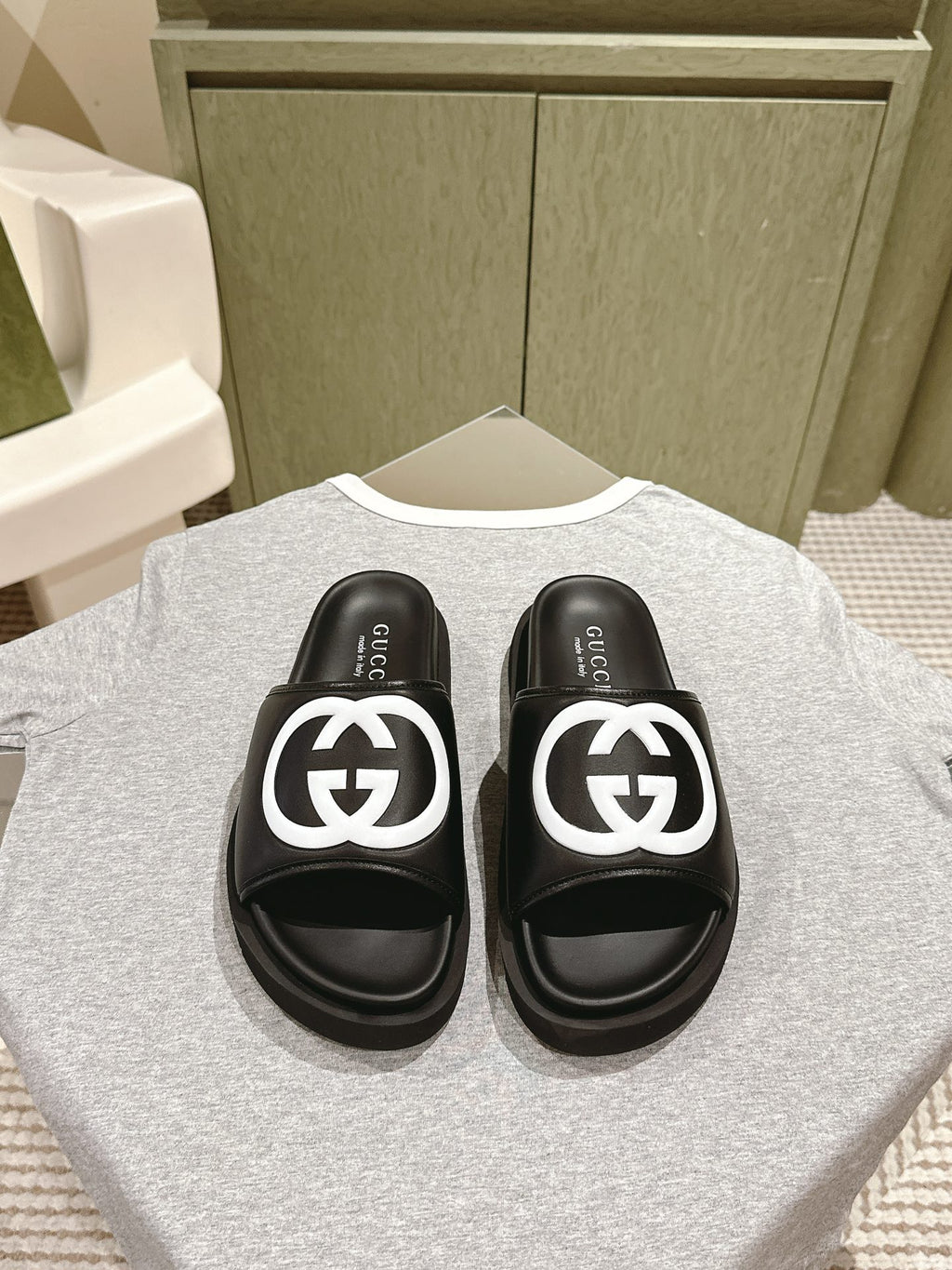 Black slide sandals with white GG logo straps and cushioned footbeds