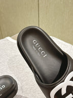 Black slide sandal with Gucci branding on footbed and white GG logo strap