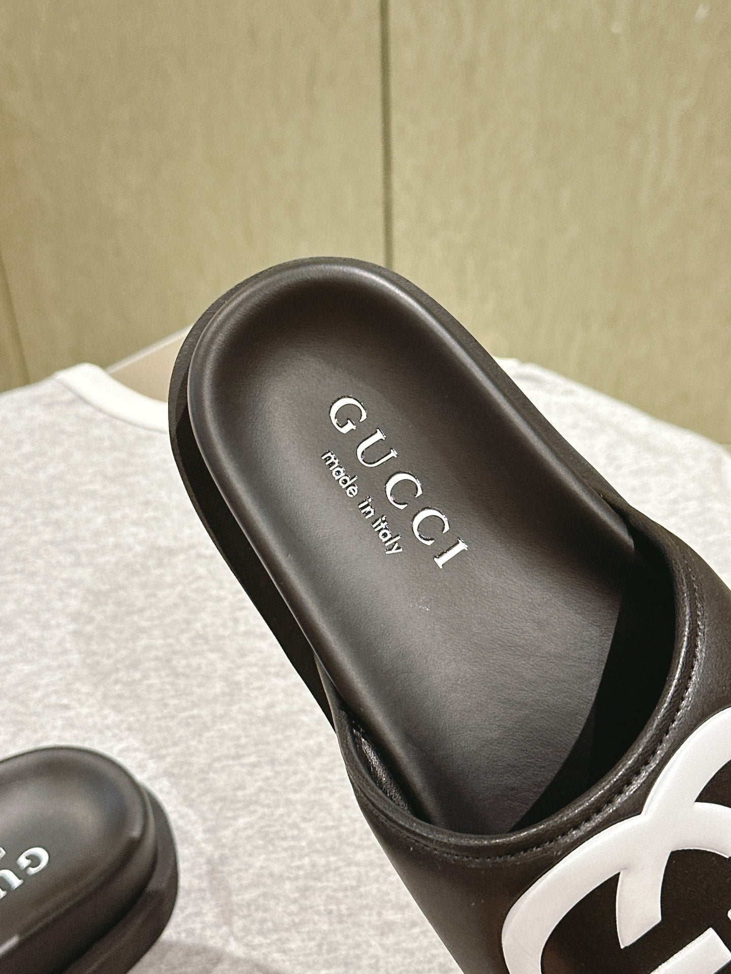 Black slide sandal with Gucci branding on footbed and white GG logo strap