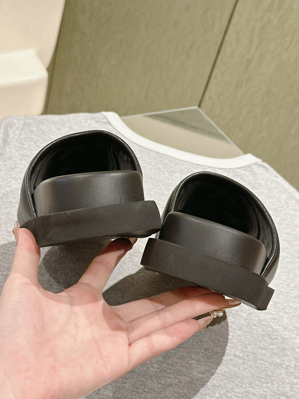 Black slide sandals with wide straps and thick soles, underside and heel view