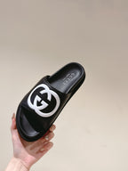 Black slide sandal with white GG logo and Gucci branding on the footbed