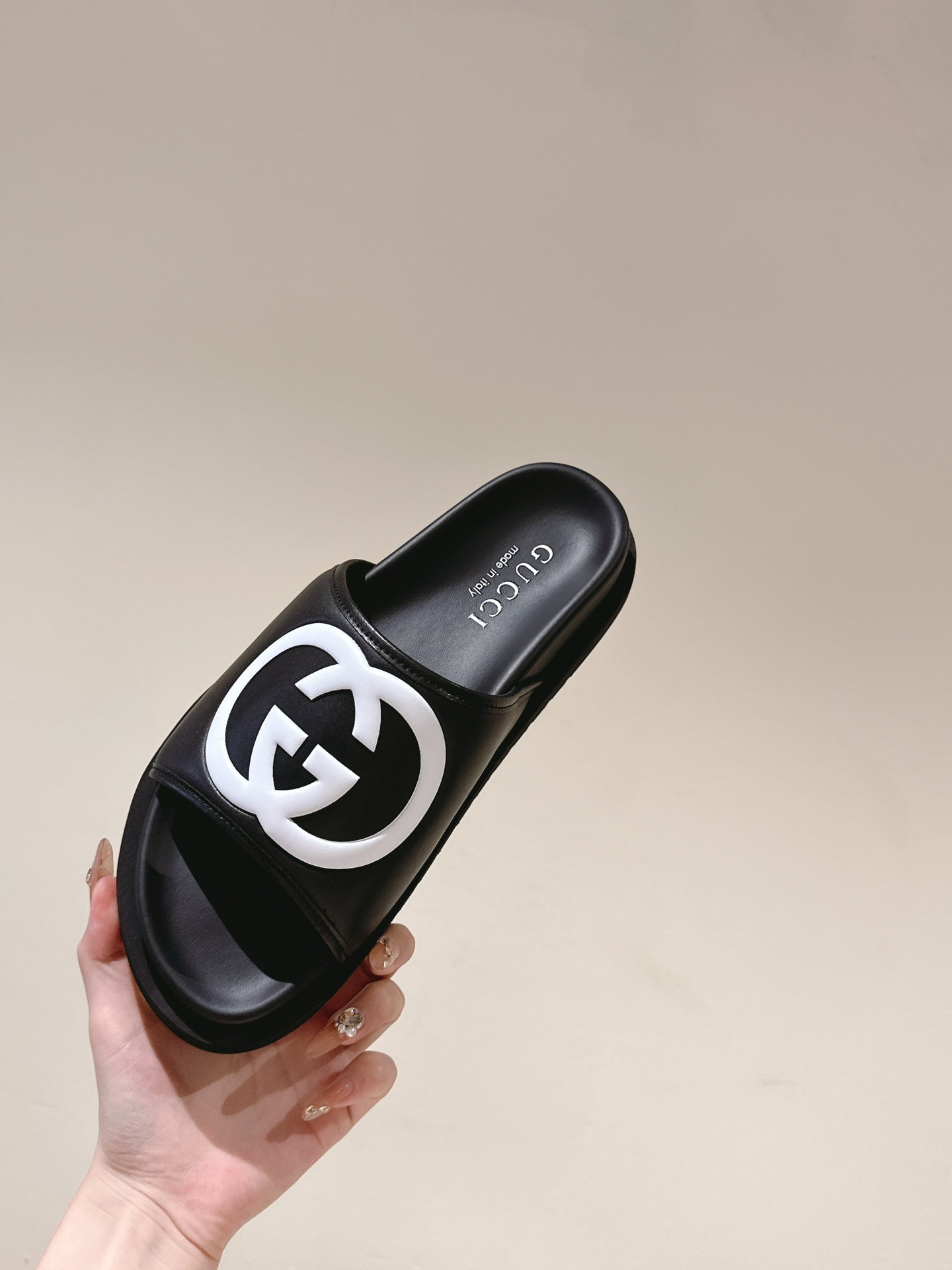 Black slide sandal with white GG logo and Gucci branding on the footbed