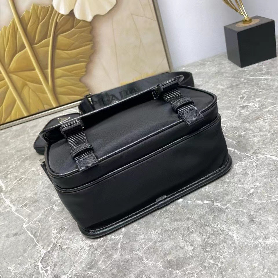 Prada black leather crossbody bag with dual front buckles and top handle straps.