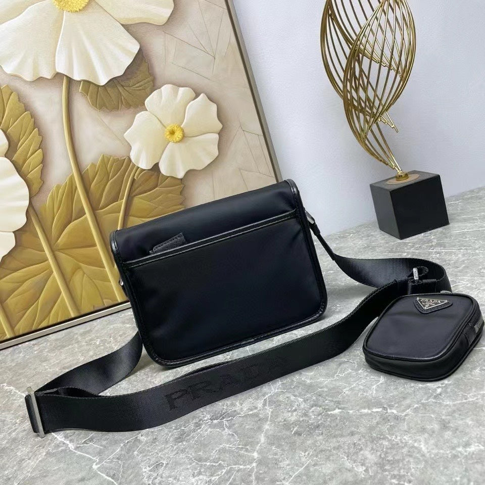 Prada black leather crossbody bag with wide strap and matching mini pouch accessory.