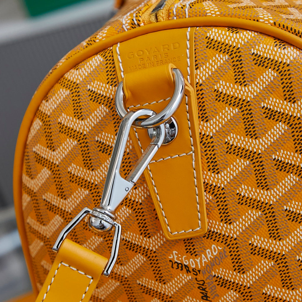 Yellow leather strap detail with metal hook hardware on patterned bag