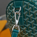 Goyard bag close-up: teal leather handle with silver clasp on patterned canvas