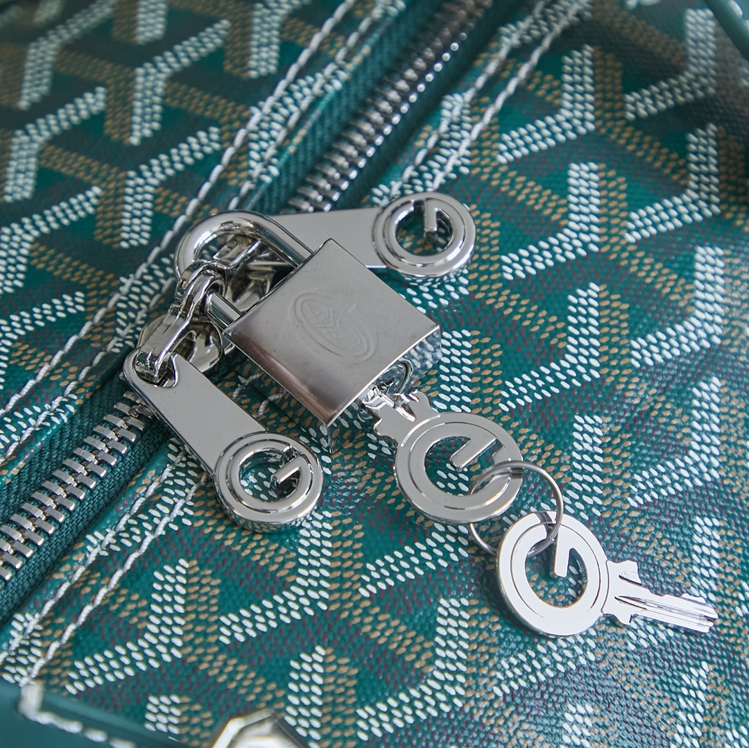 Goyard bag close-up: silver zipper pull and rings on teal patterned canvas