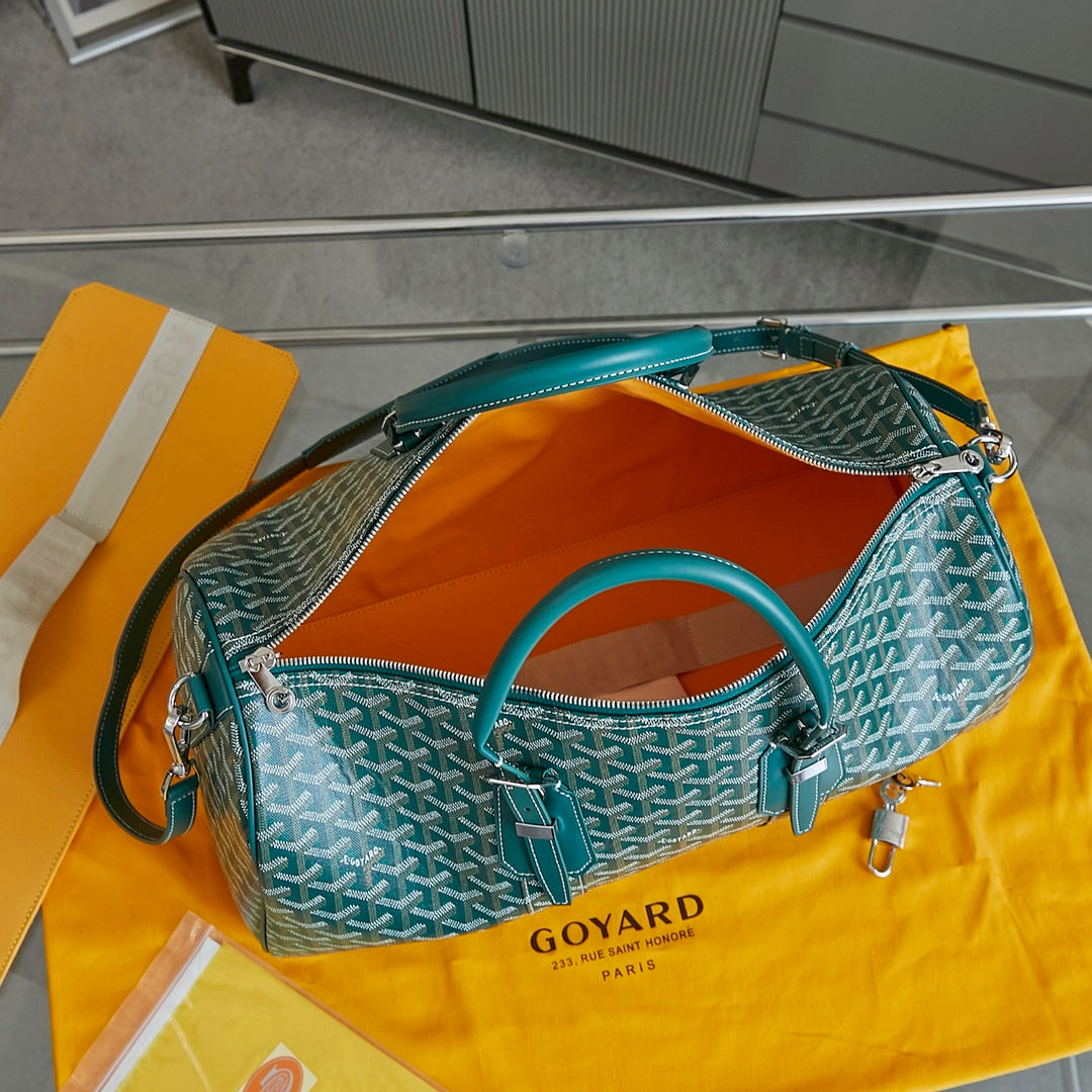 Goyard bag in teal with white pattern, open top showing orange interior lining