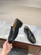 Prada unisex black loafers held in hand, rounded toe and strap detail