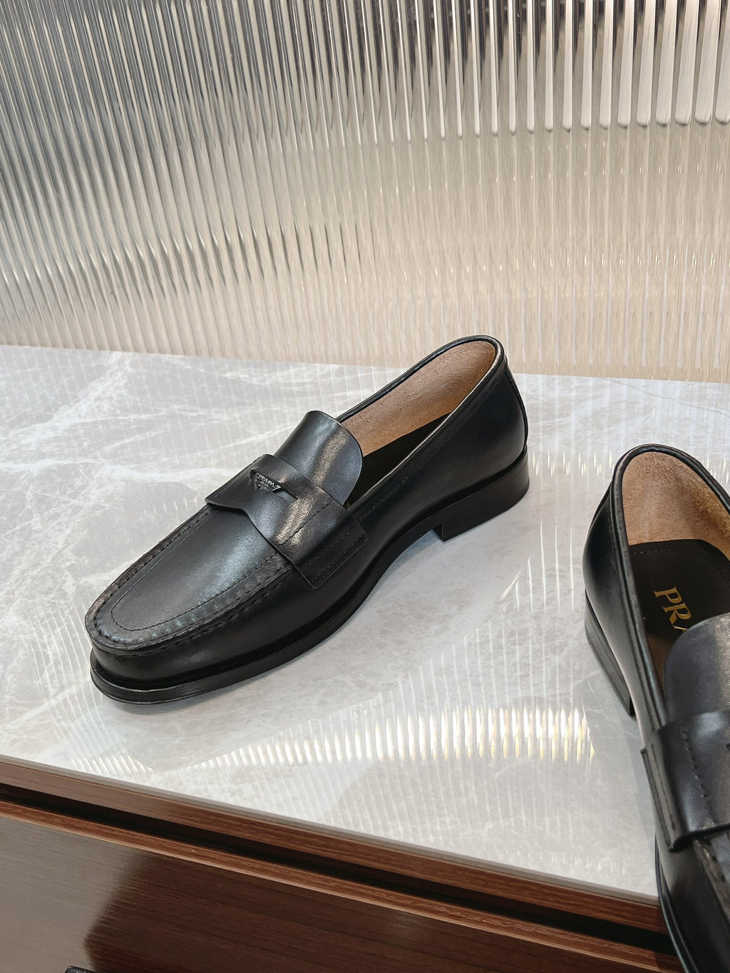 Prada unisex black loafers, front and side angles on display surface