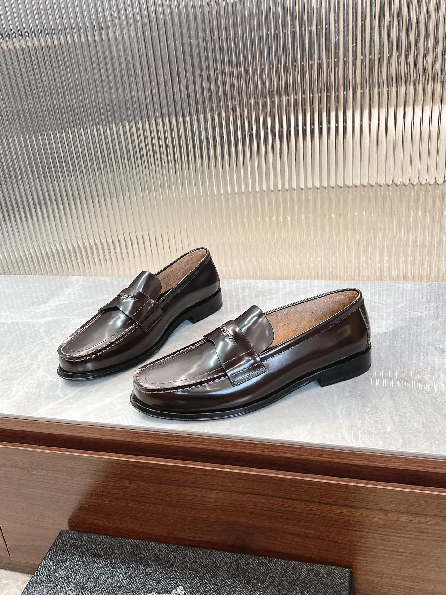 Prada unisex leather loafers, dark brown, angled view with stitched trim