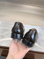 Prada unisex leather loafers, dark brown, heel and toe view held in hand