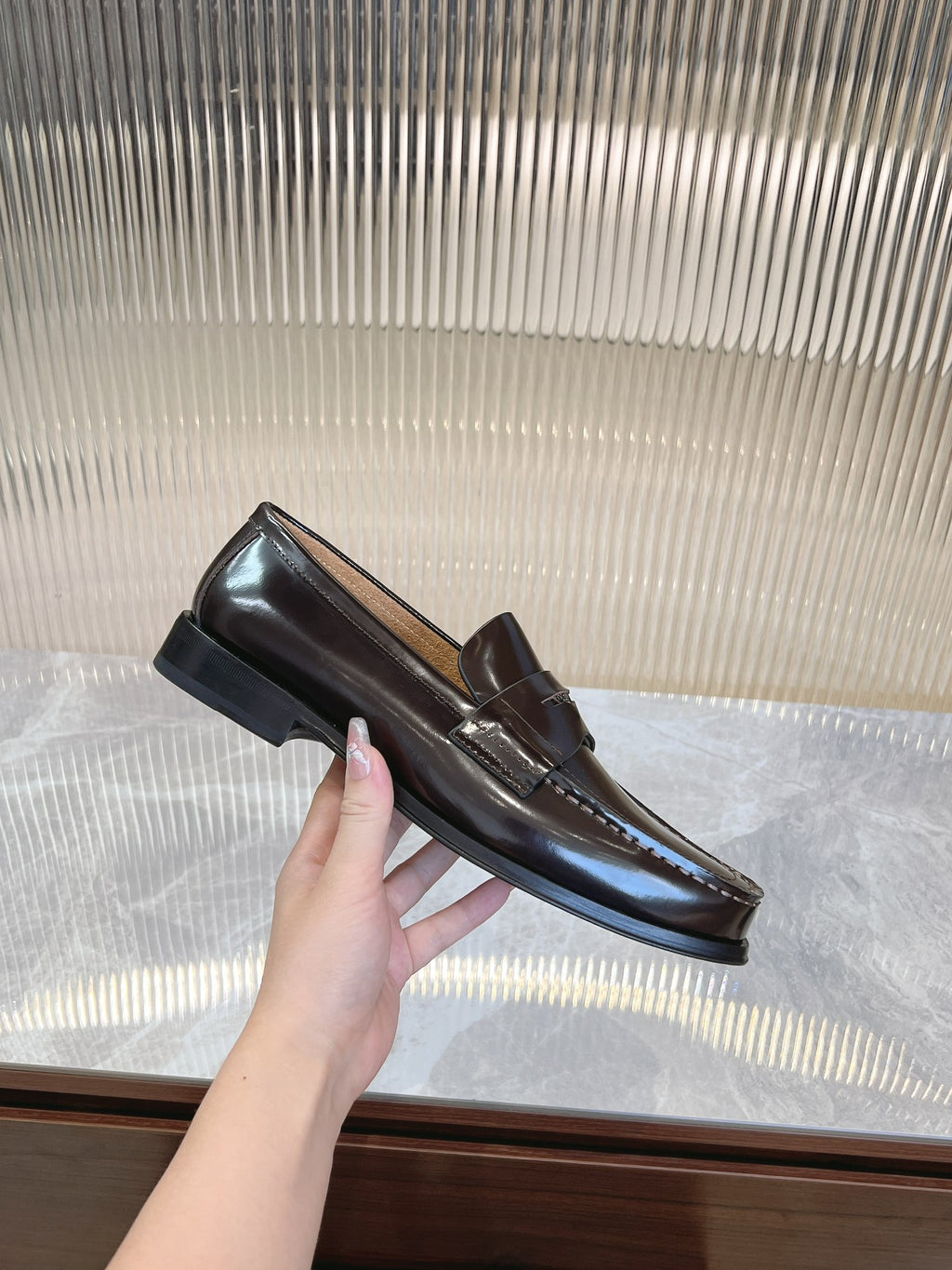 Prada unisex leather loafers in dark brown, hand holding one shoe