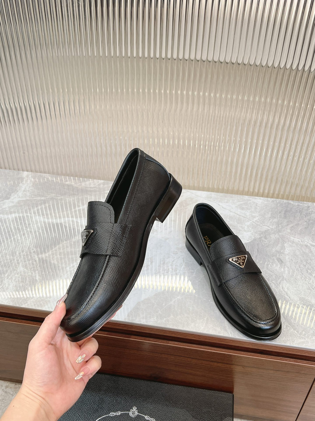Prada unisex leather loafers, dark textured finish, side metal badge, slip-on design