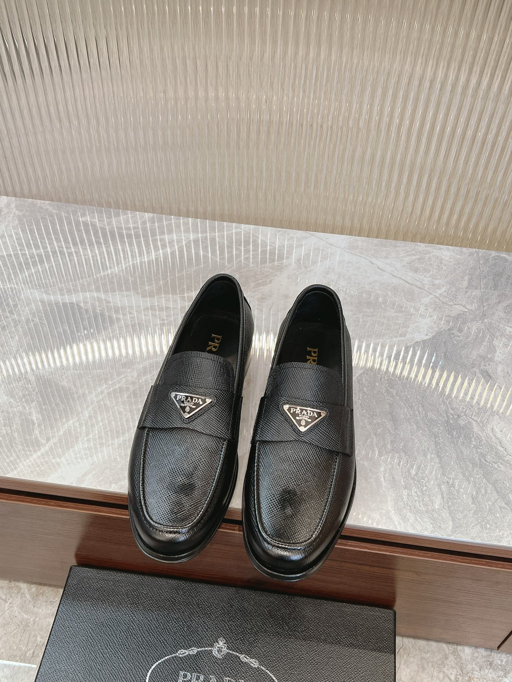 Prada unisex leather loafers, dark textured upper, metal logo detail on vamp