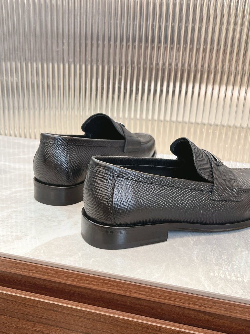 Prada unisex loafers pair, dark textured leather, back view with low block heel