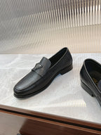 Prada unisex loafers in dark leather, low heel sole and metal logo badge on strap
