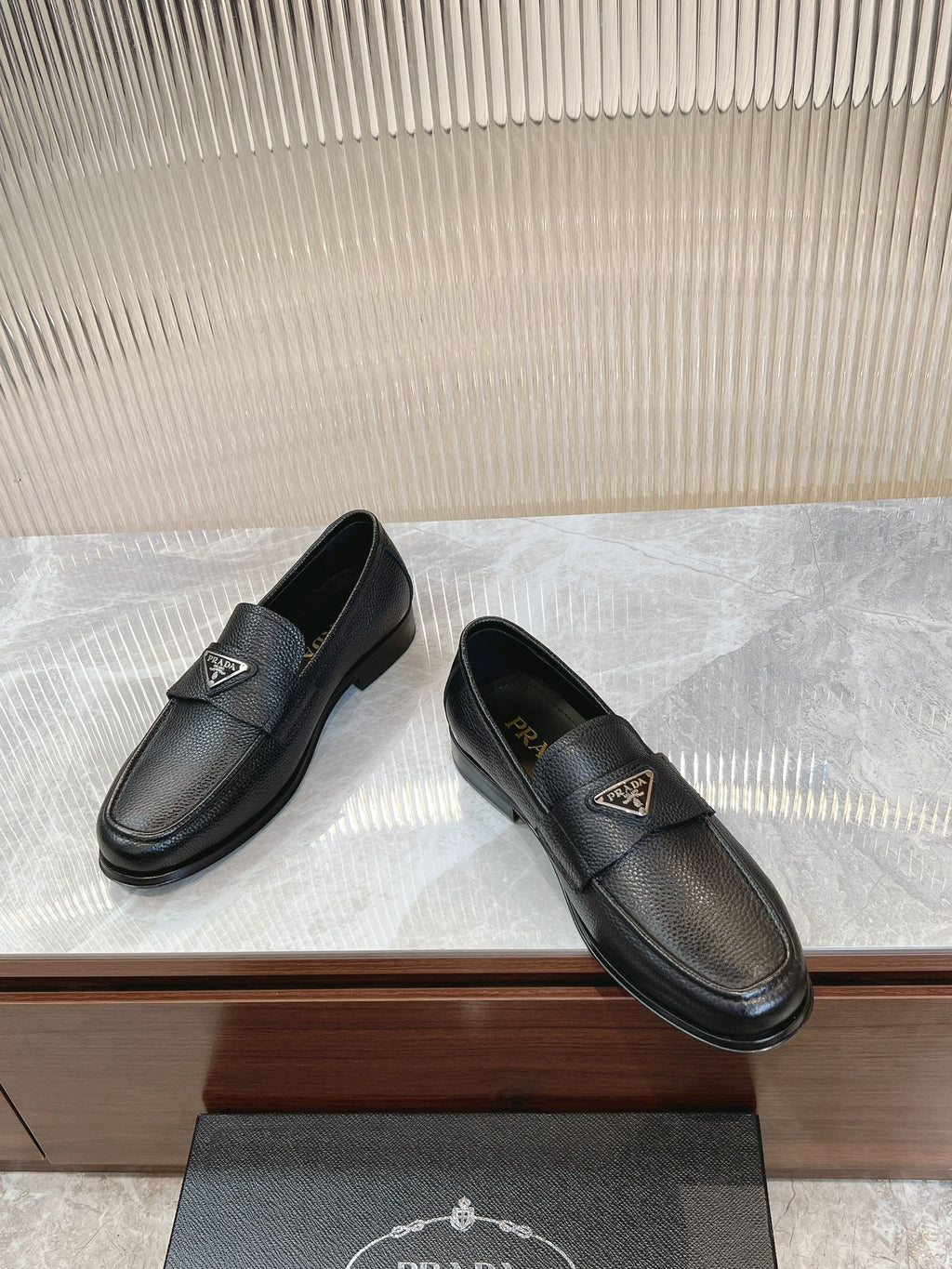 Prada unisex loafers, dark leather upper with small metal logo badge, side view