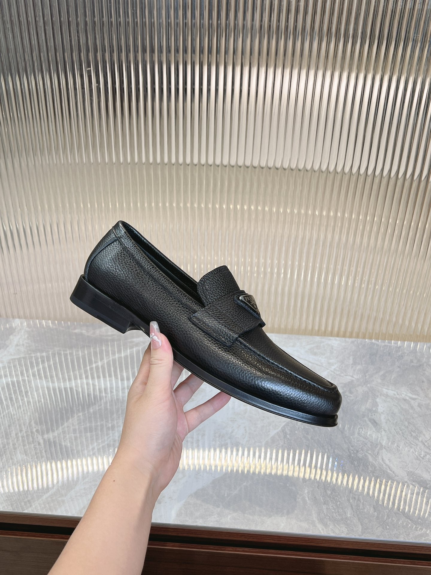Prada unisex loafers in dark textured leather, lifted side view of loafer upper