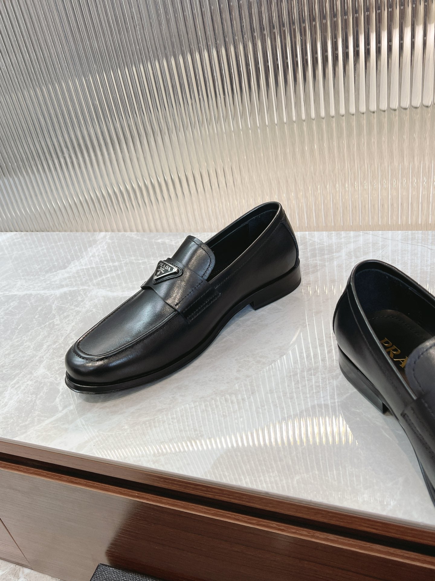 Black leather loafer pair, rounded toe and low heel with logo detail.