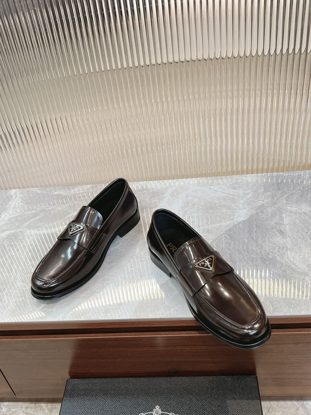 Pair of dark brown leather Prada unisex loafers with square metal logo plate