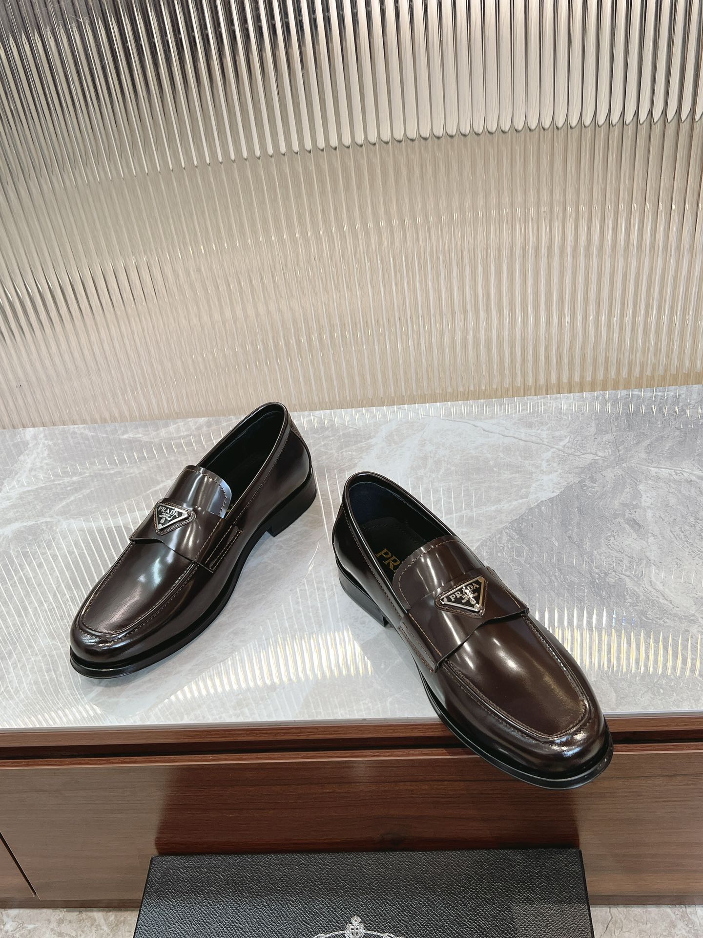 Pair of dark brown leather Prada unisex loafers with square metal logo plate