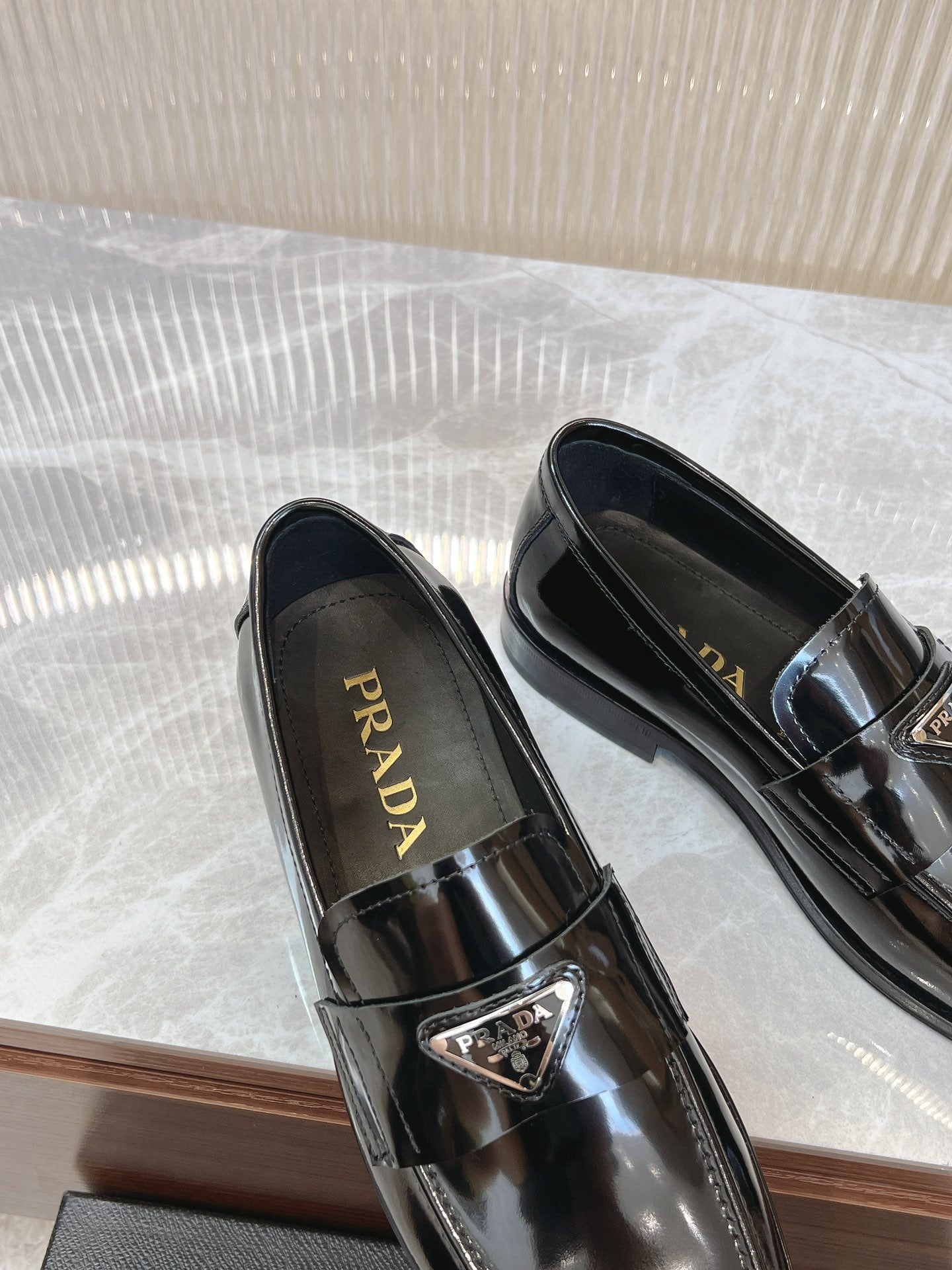Prada unisex loafers, dark patent leather, top view showing logo on insoles
