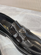 Prada unisex loafer buckle close-up on dark patent leather