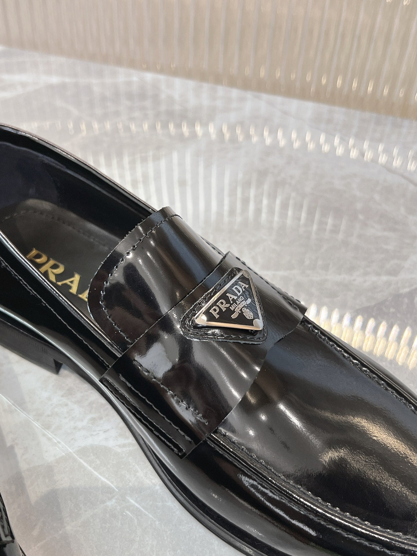 Prada unisex loafer buckle close-up on dark patent leather
