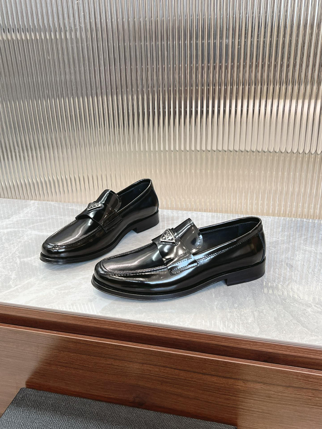 Prada unisex loafers in dark patent leather with metallic buckle, angled view