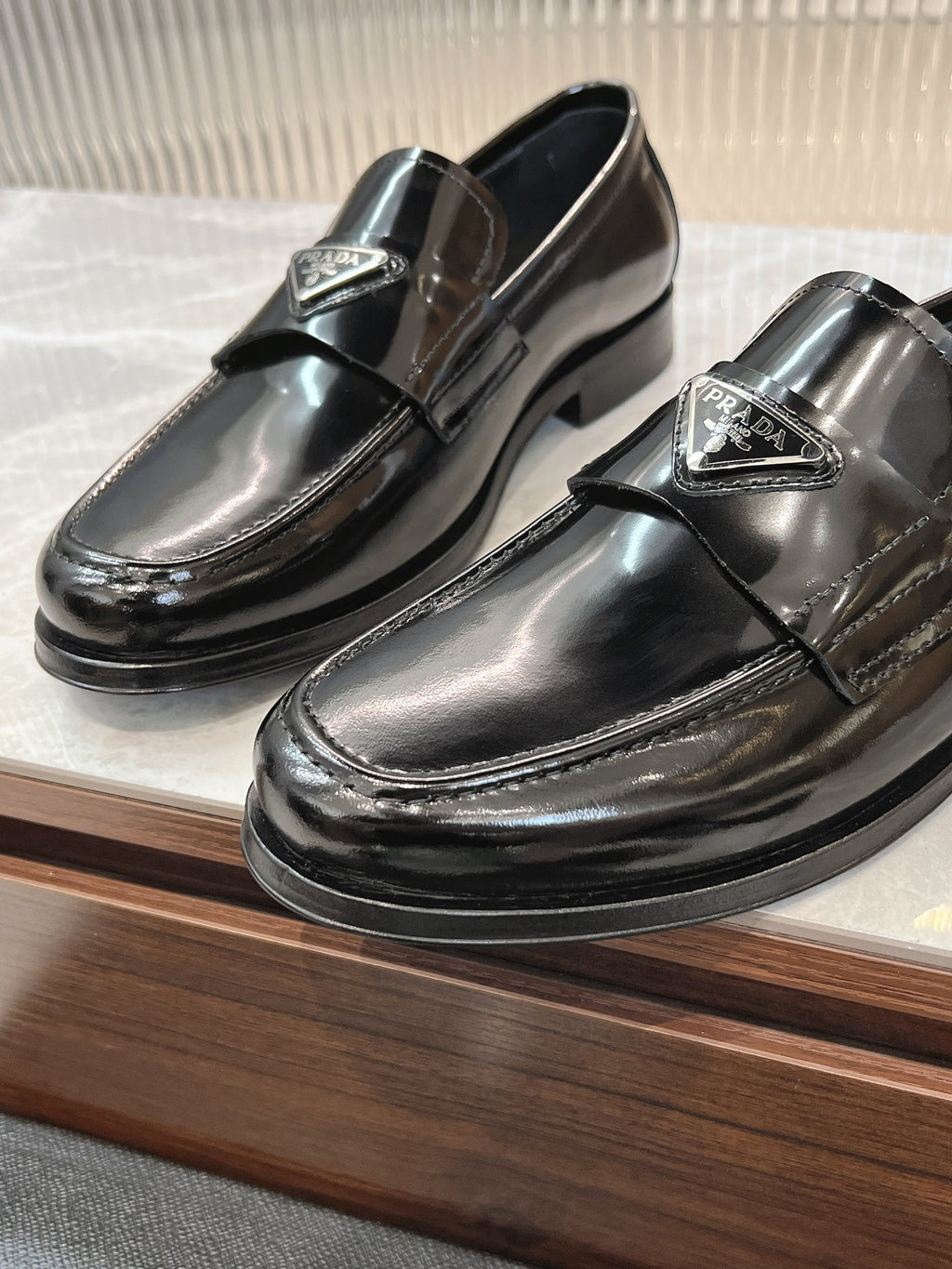Prada unisex loafers, dark patent leather, front angled pair