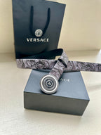 Versace belt with gray floral strap and round logo buckle, shown on box