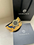 Belt with gold-and-blue baroque print and round Versace logo buckle, close angle.