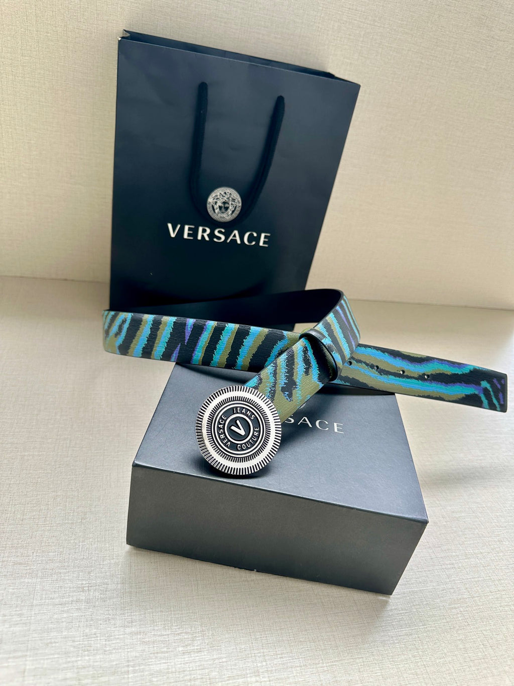 Versace belt with teal-blue patterned strap and oversized round silver buckle
