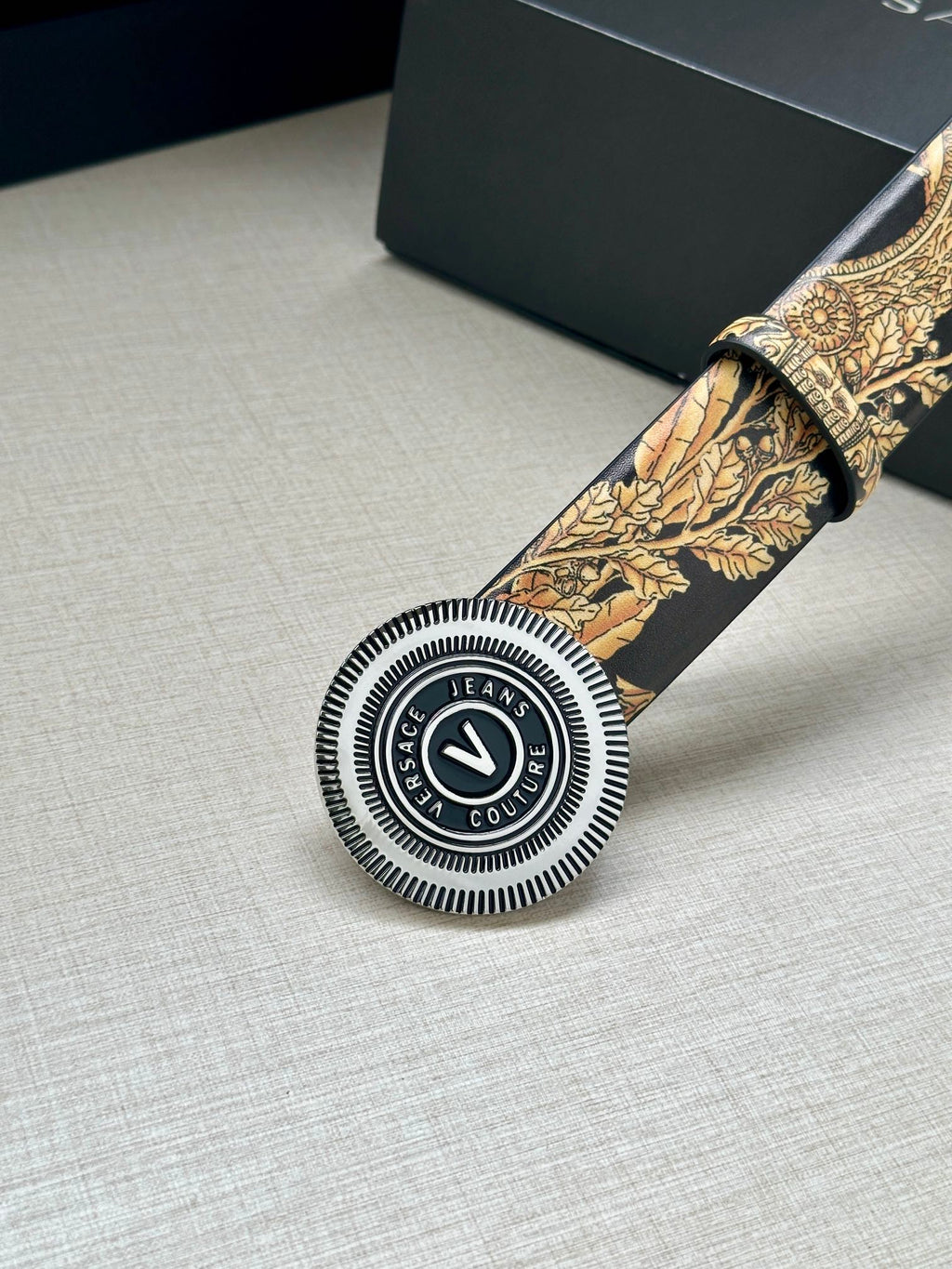 Versace belt detail: circular buckle and gold baroque print on dark strap