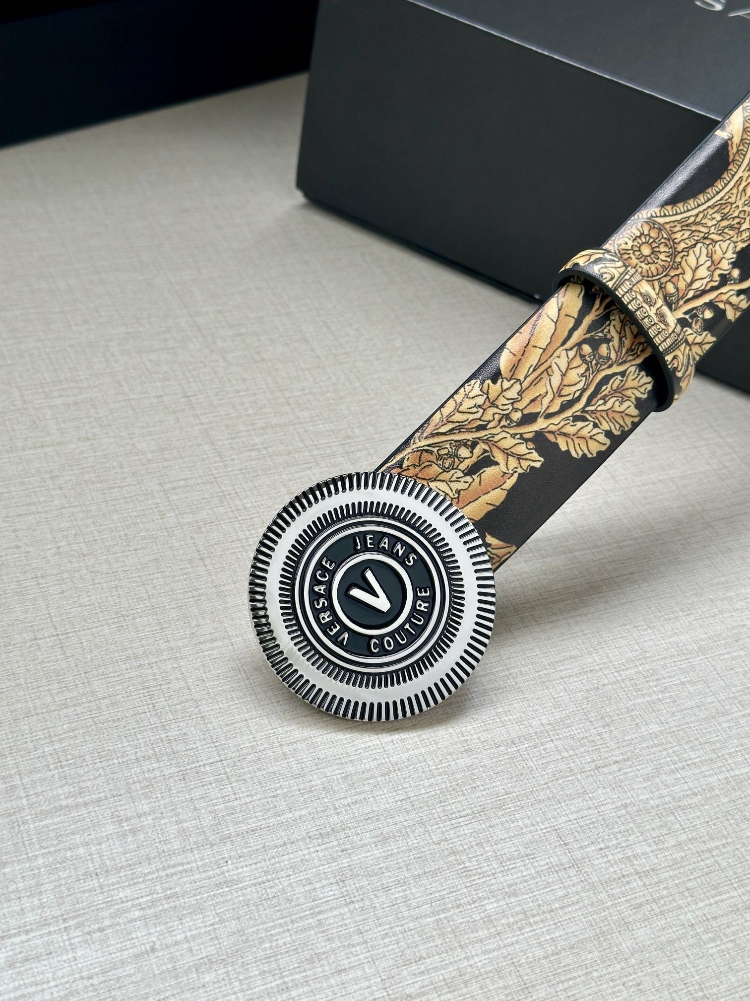 Versace belt detail: circular buckle and gold baroque print on dark strap