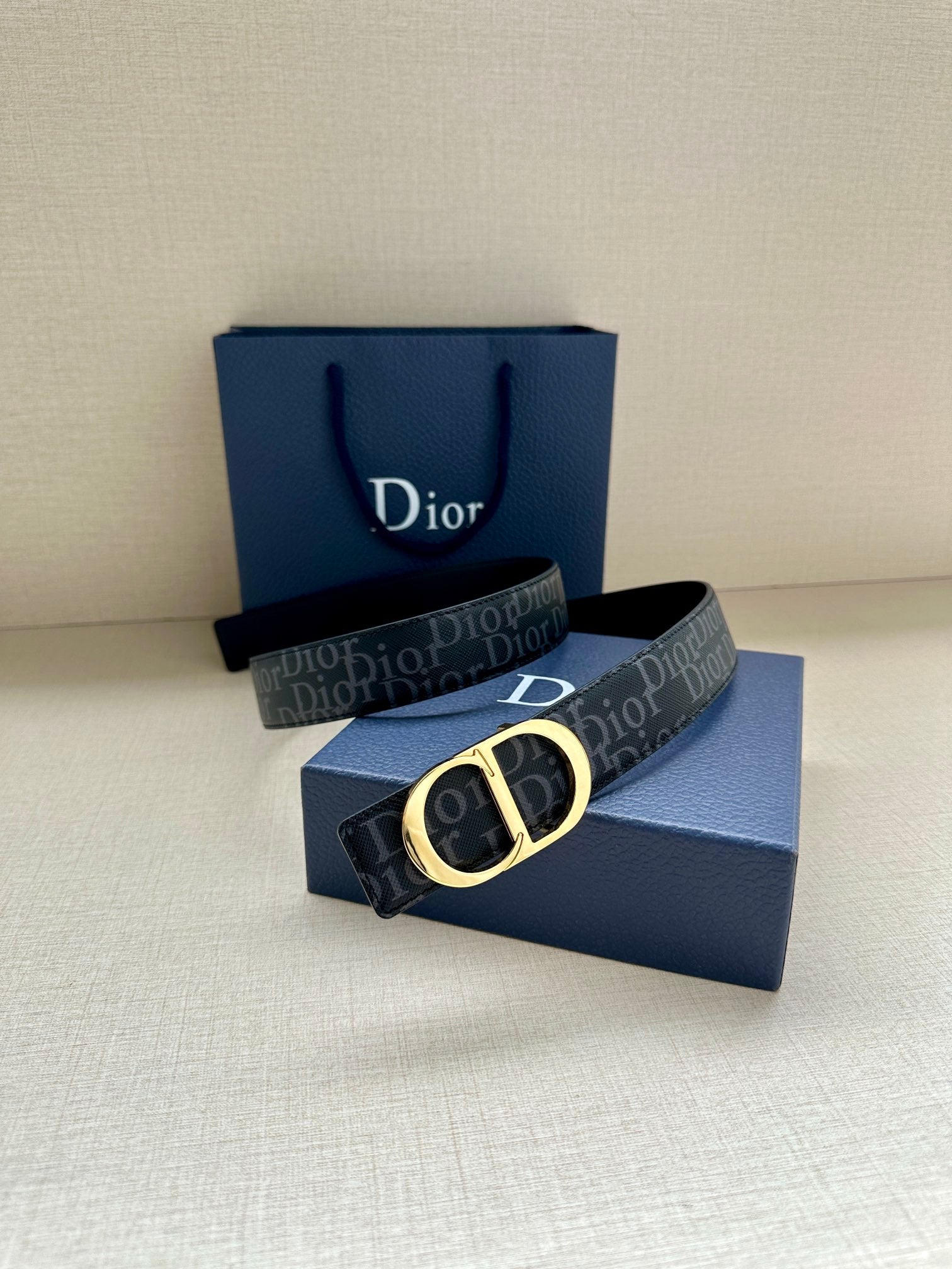 Dior belt with dark monogram strap and gold CD buckle, laid on box