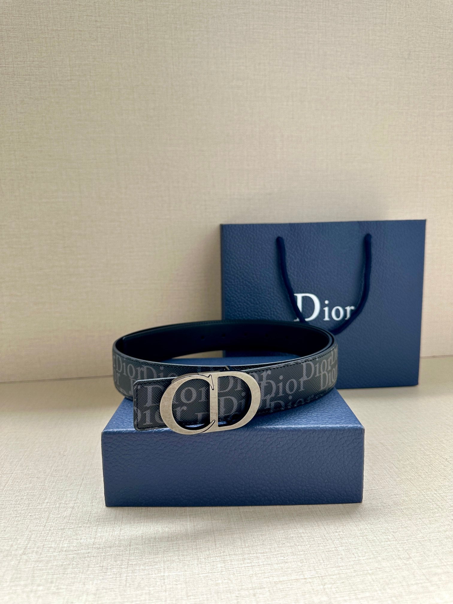 Dior belt with dark monogram strap and silver CD buckle, on blue packaging