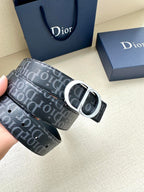 Dior belt with dark monogram strap and silver buckle, held in hand