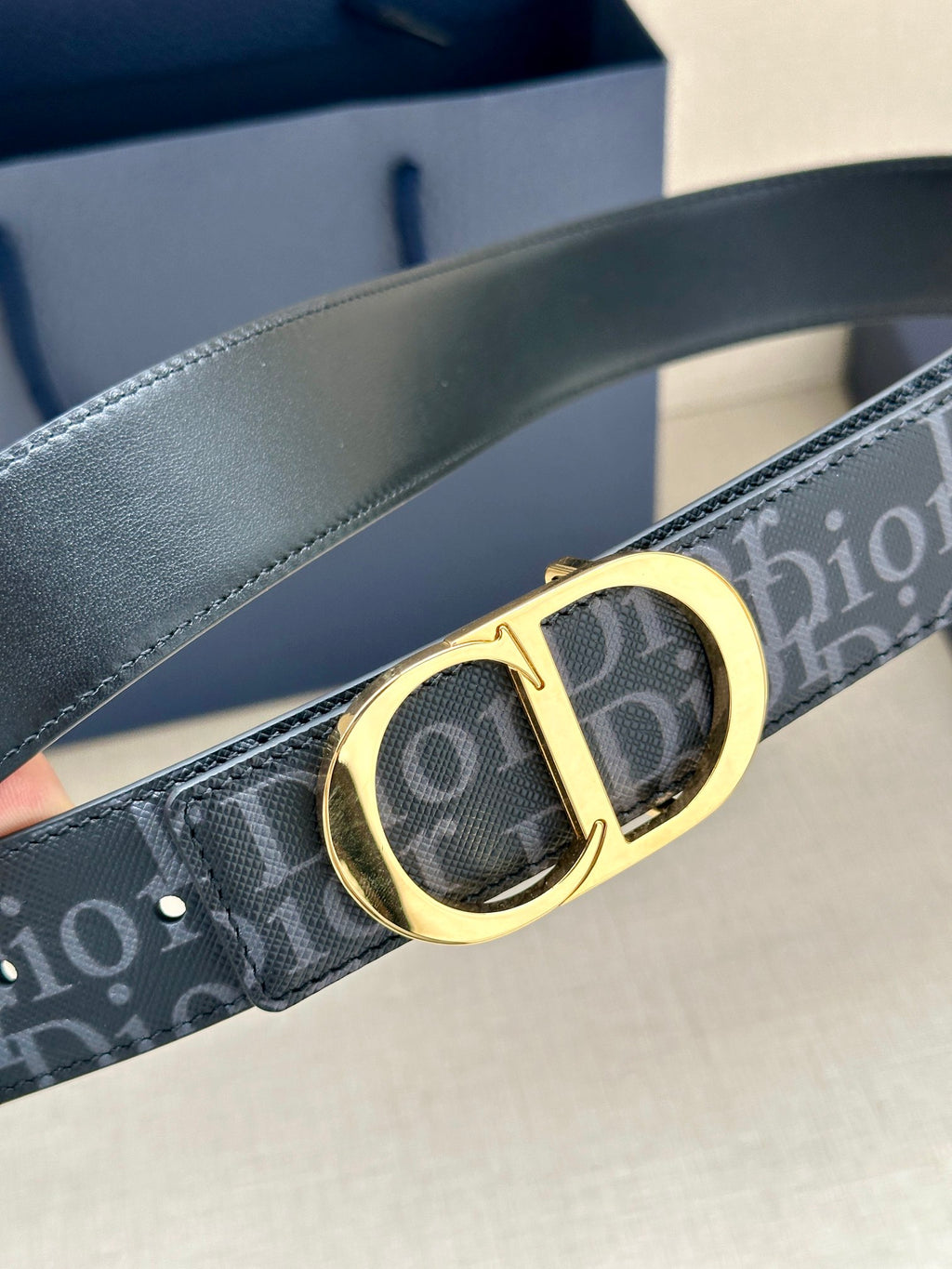 Dior belt close-up: dark monogram strap with gold CD buckle and contrast stitching