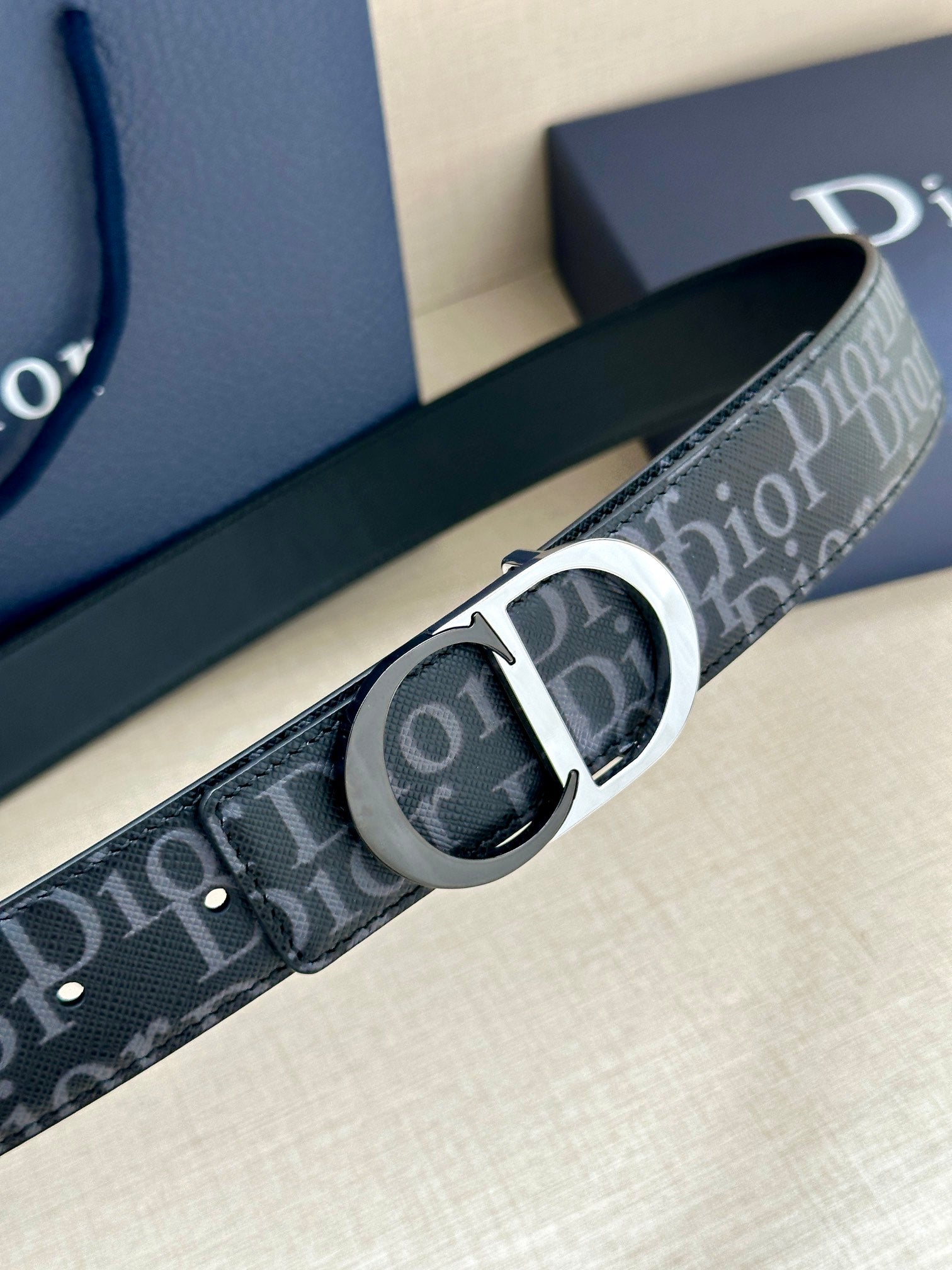 Dior Oblique belt close-up with silver CD buckle on dark blue strap