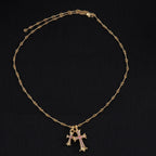 Gold cross pendant necklace with purple stone accents and linked chain