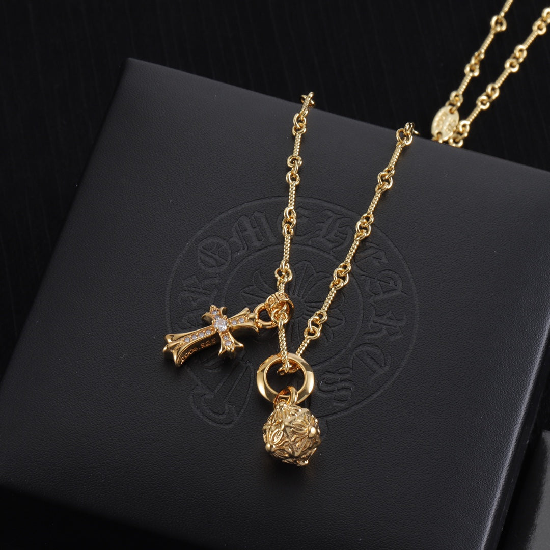 Gold-tone pendant necklace set with cross and round charm, on display card