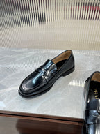 Prada unisex black leather loafer, side profile with metal strap and stitched edge.