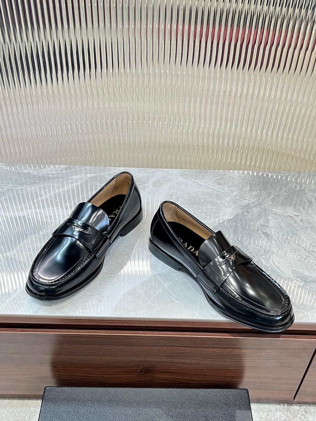 Prada unisex black leather loafers, side-by-side view, metal strap detail on vamp.